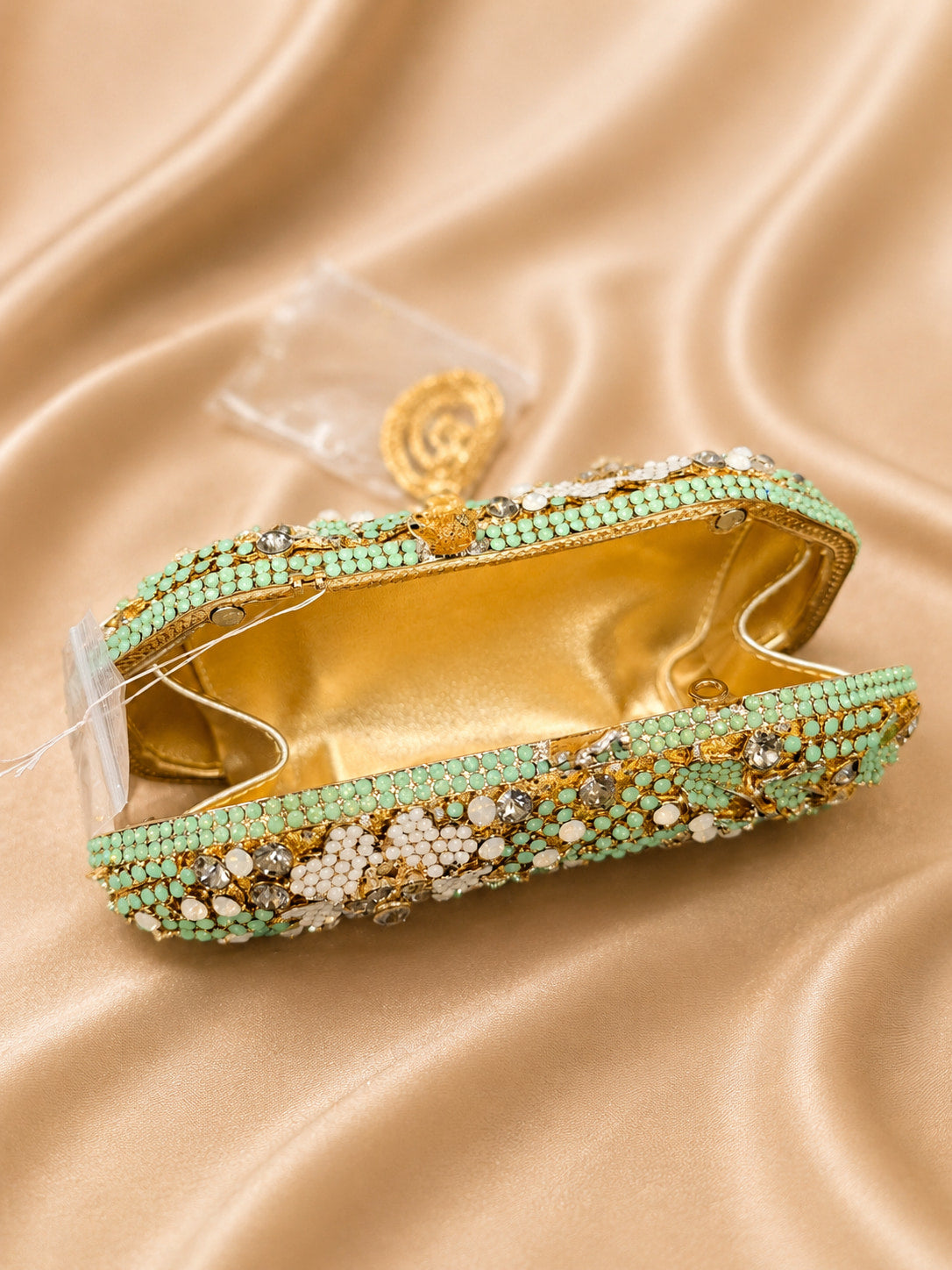 Decorative headband with green and gold beads on a beige fabric background