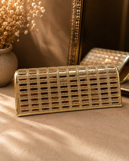 Gold clutch with intricate design on a beige surface