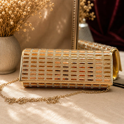 Gold clutch with chain strap on a beige surface with decorative elements